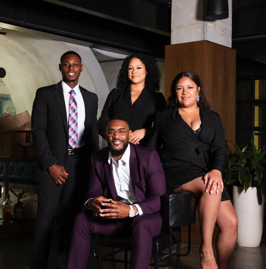 Group portrait of four people in dark suits